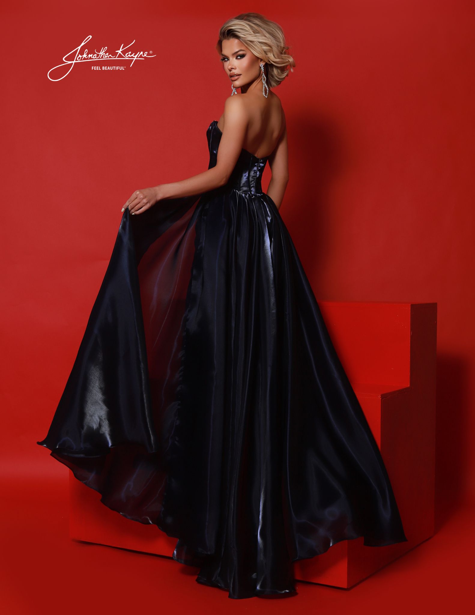 Back view of navy strapless fitted pageant gown with overskirt. Luxe mirror organza finish with full dramatic train and corset-inspired detailing, great for pageant or formal red carpet events. 2025 pageant gown, navy blue pageant gown, pageant gown with overskirt. 2025 homecoming court dress